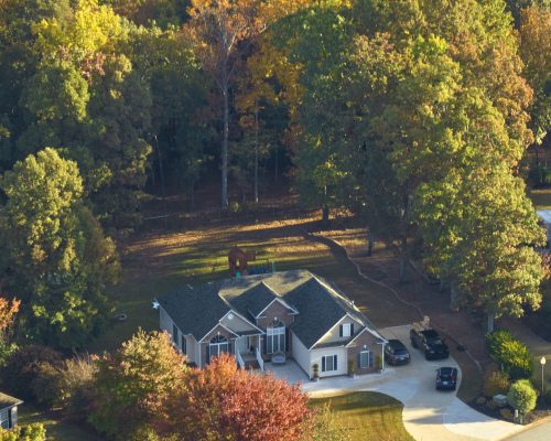 View from above of expensive residential house between yellow fall trees in suburban area in South Carolina. American dream home as example of real estate development in US suburbs View from above of expensive residential house between yellow fall trees in suburban area in South Carolina. American dream home as example of real estate development in US suburbs.